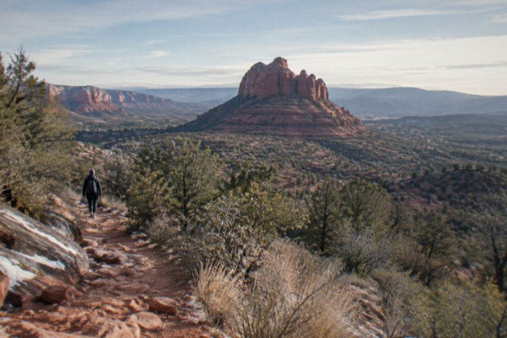 A red rock butte above Sedona with dry scrub and a wide desert sky