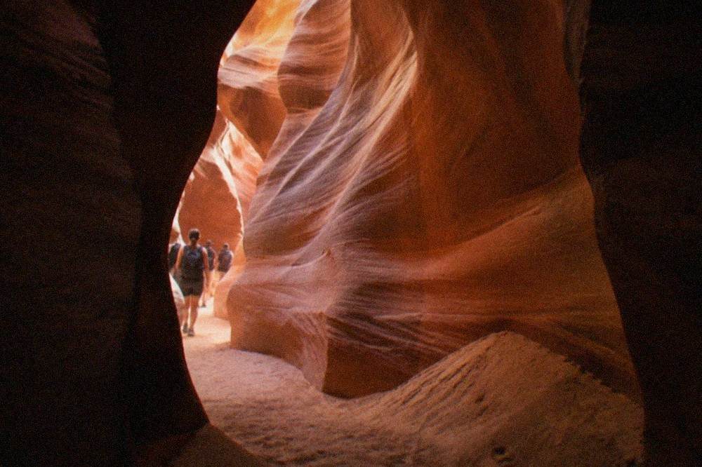 Sunlight beams falling between narrow red sandstone walls inside a slot canyon