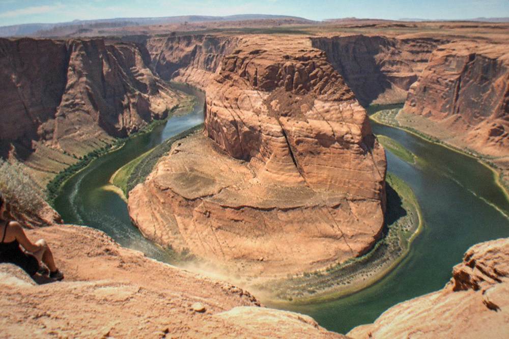 The Colorado River curving around a tall red sandstone cliff at Horseshoe Bend
