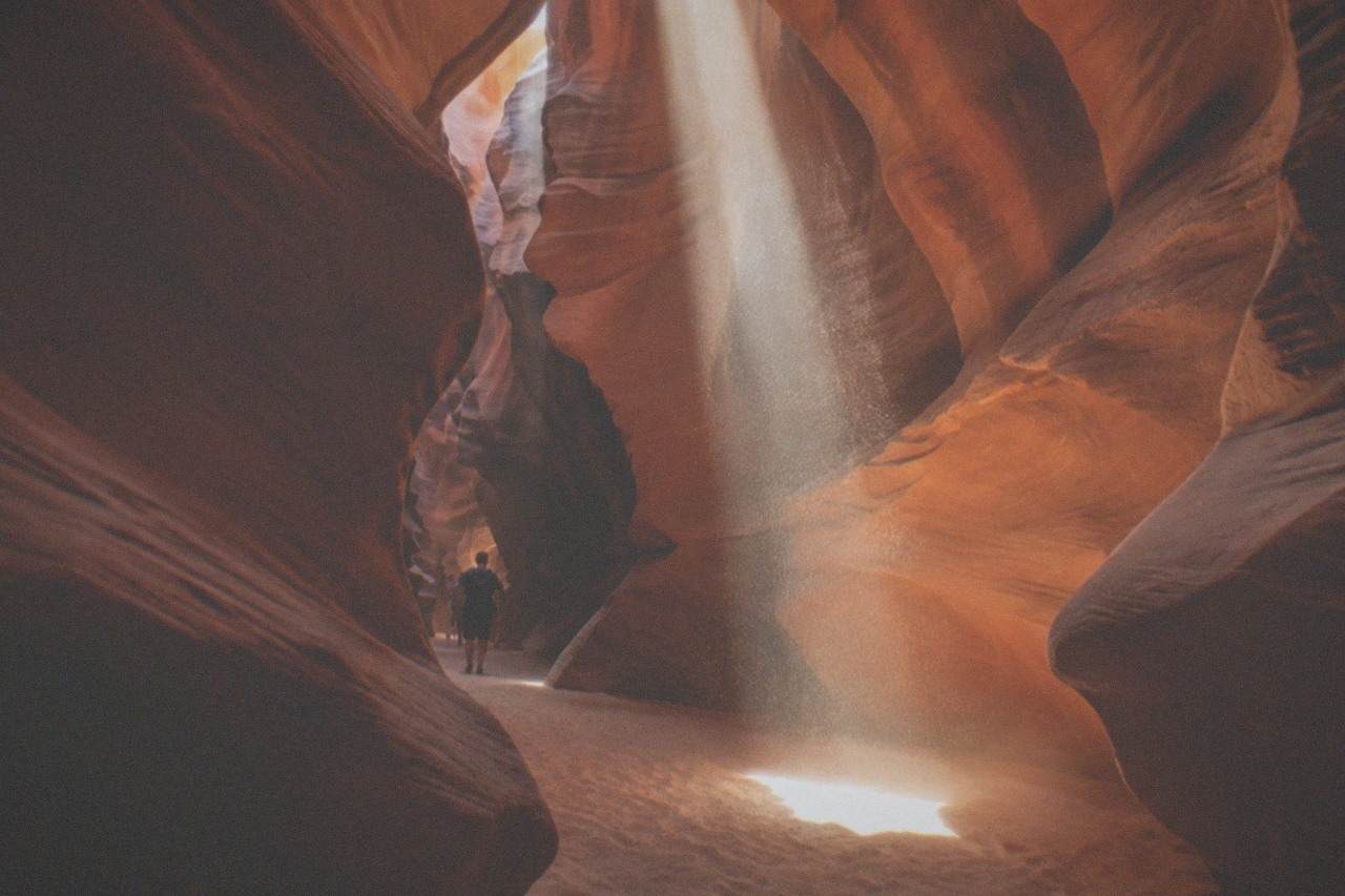 Sunlight beams falling between narrow red sandstone walls inside a slot canyon