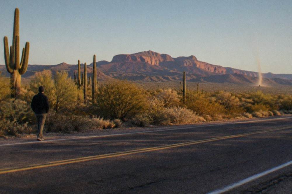 Desert highway heading north from Phoenix with distant red rock mesas under a clear sky