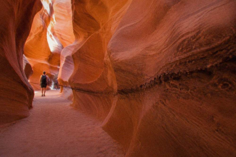 Sunlit sandstone corridor inside a narrow slot canyon with smooth curved walls