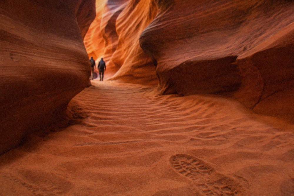 Narrow curving sandstone walls of a slot canyon glowing orange in reflected light