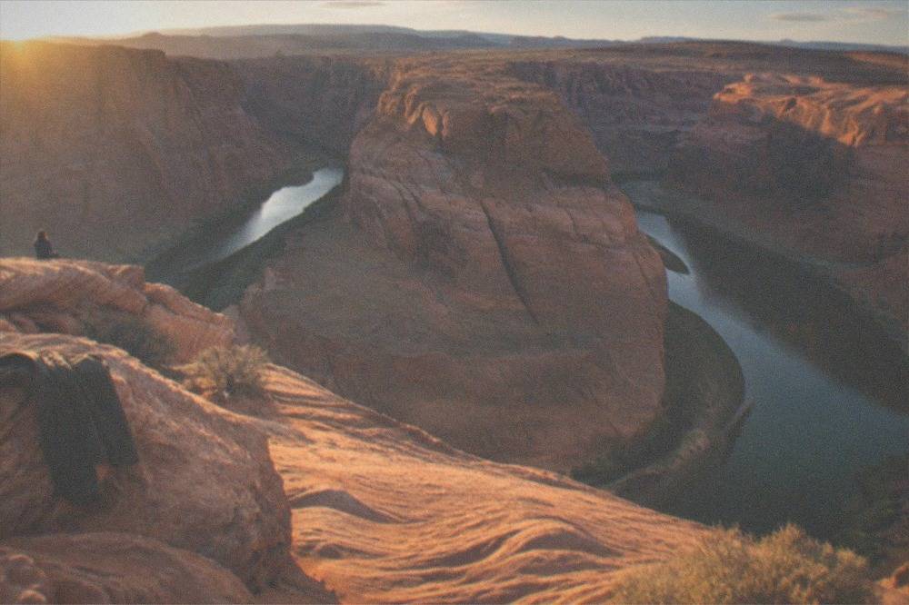 A wide desert overlook above a river bending in a deep sandstone gorge at golden hour
