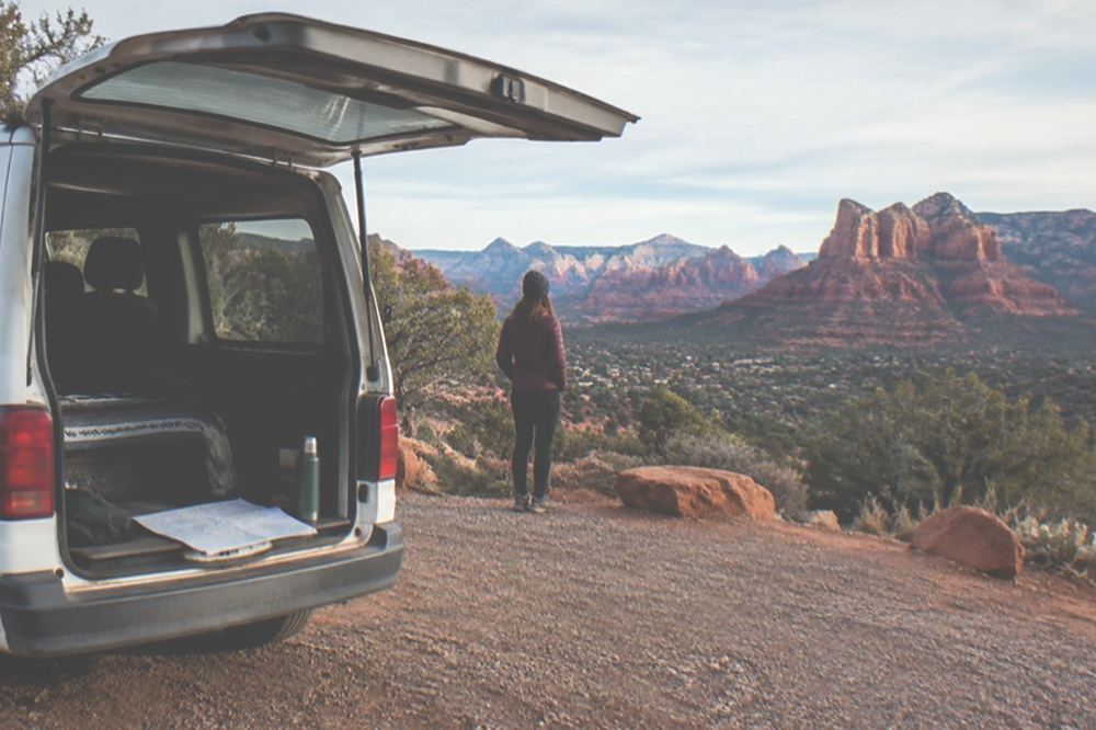 A small van parked at a red rock overlook in late afternoon light