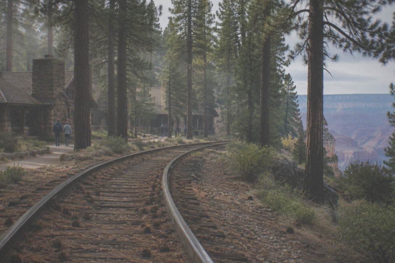 Vintage railway tracks curving through pine forest toward the Grand Canyon South Rim
