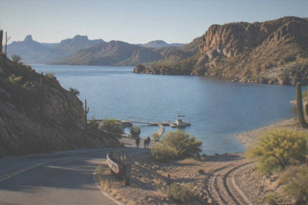 A desert lake surrounded by rocky hills along a winding paved road