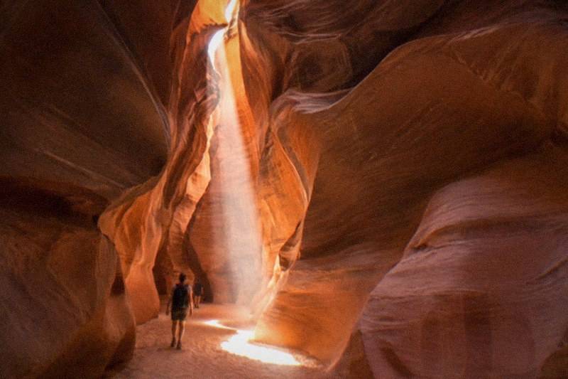 A beam of daylight cuts the twisted sandstone walls of Antelope Canyon, warm orange stone curving overhead.