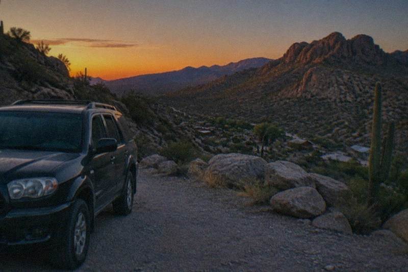 A private touring SUV stands ready at a desert overlook, red rock country and open sky spreading out beyond the windshield.