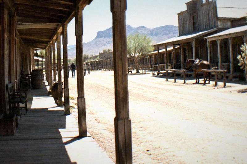 Sunlight falls on wooden storefronts and boardwalks along Tombstone's main street, the old mining town quiet in afternoon heat.