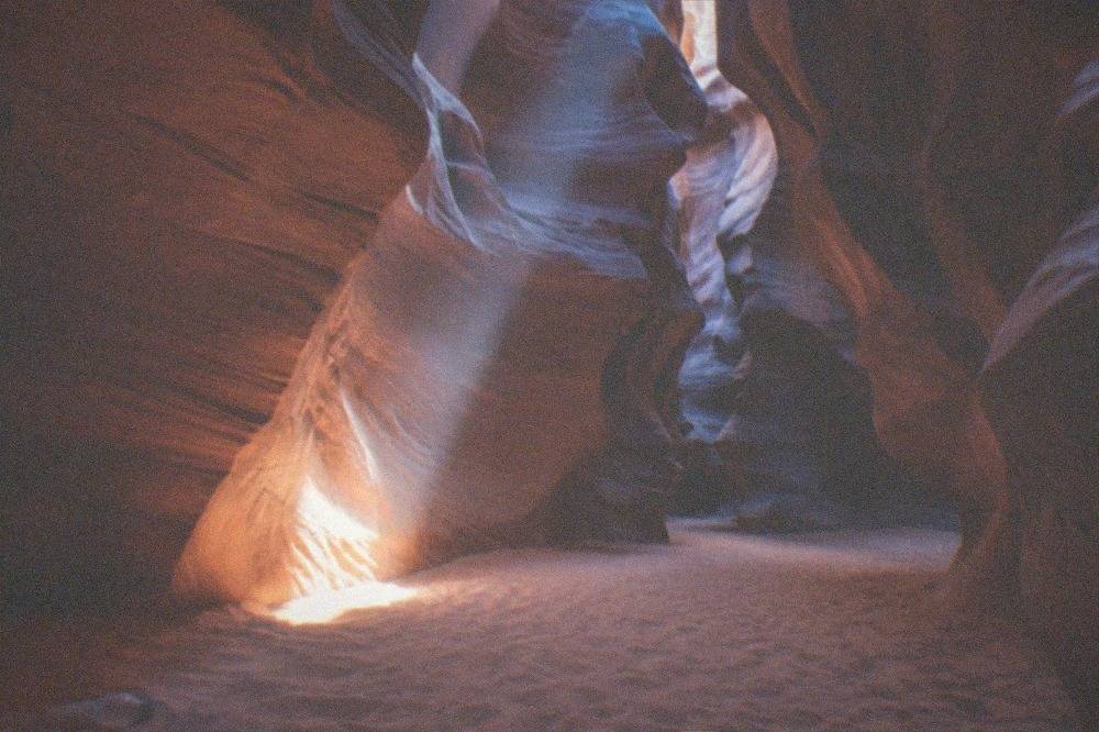 Sunlight cutting through a narrow gap between tall sandstone canyon walls