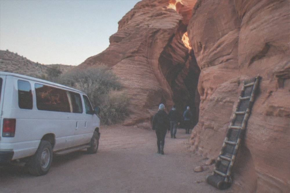 A tour van parked at a red rock overlook in the early morning