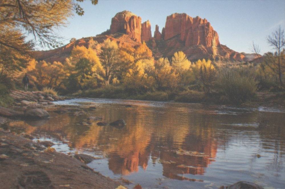 Red sandstone formations in Sedona with Cathedral Rock glowing in late afternoon light