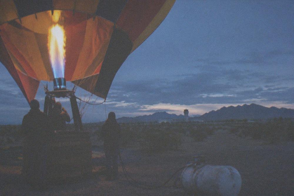 Balloon crew inflating a hot air balloon on a desert launch field before sunrise