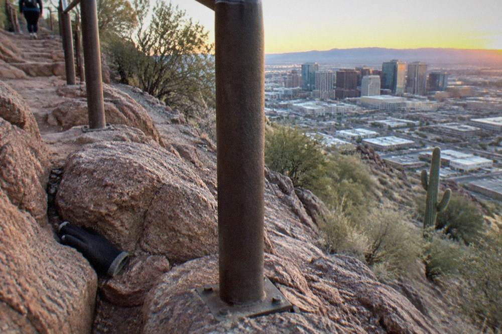 Red rock steps and a metal handrail climbing a steep desert slope in early light