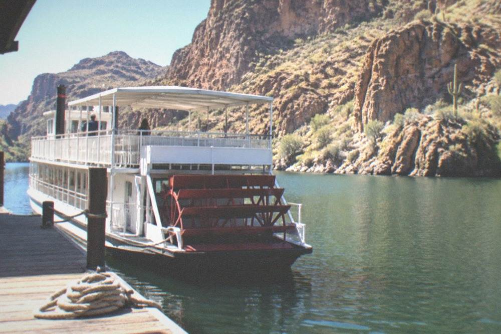 A tour boat tied at a dock on Canyon Lake beneath canyon walls