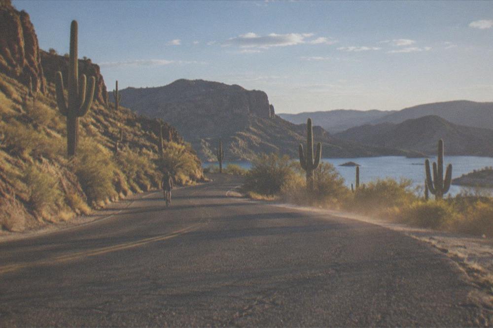 A paved desert road curving toward canyon hills near Canyon Lake