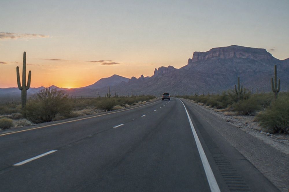 Highway stretching north through desert scrubland toward distant mesas in early morning light