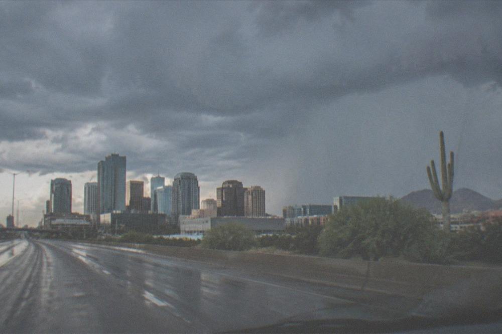 Storm clouds gathering over a desert highway with rain falling in the distance