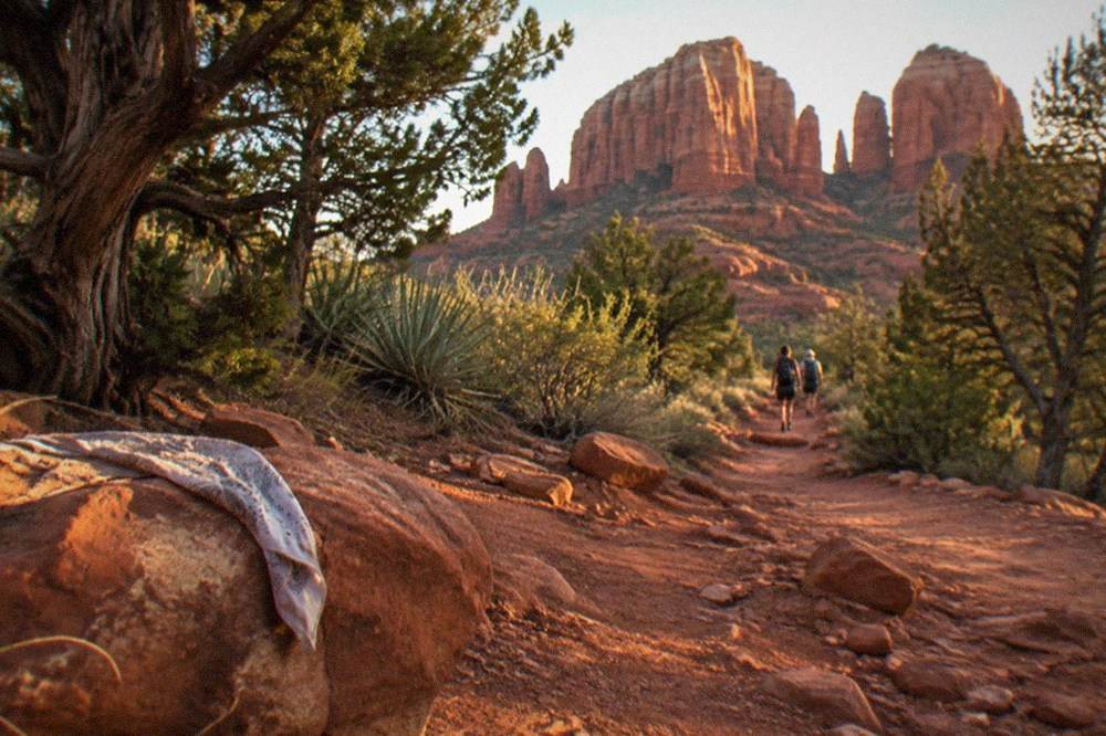 Red rock formations in Sedona under afternoon light with juniper trees in the foreground