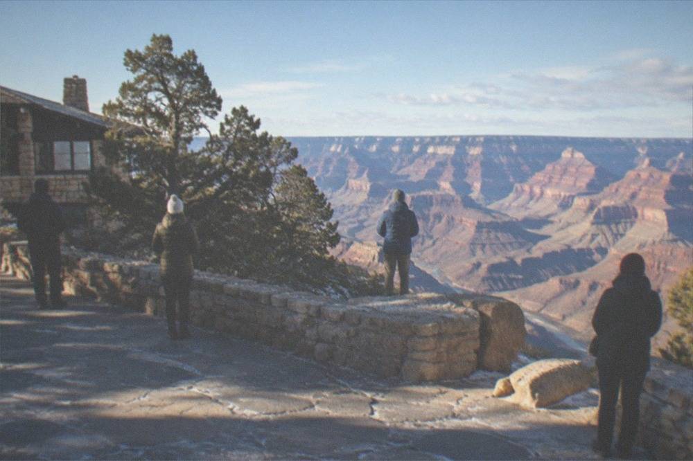A small group of travelers standing at a South Rim viewpoint with the canyon spreading below