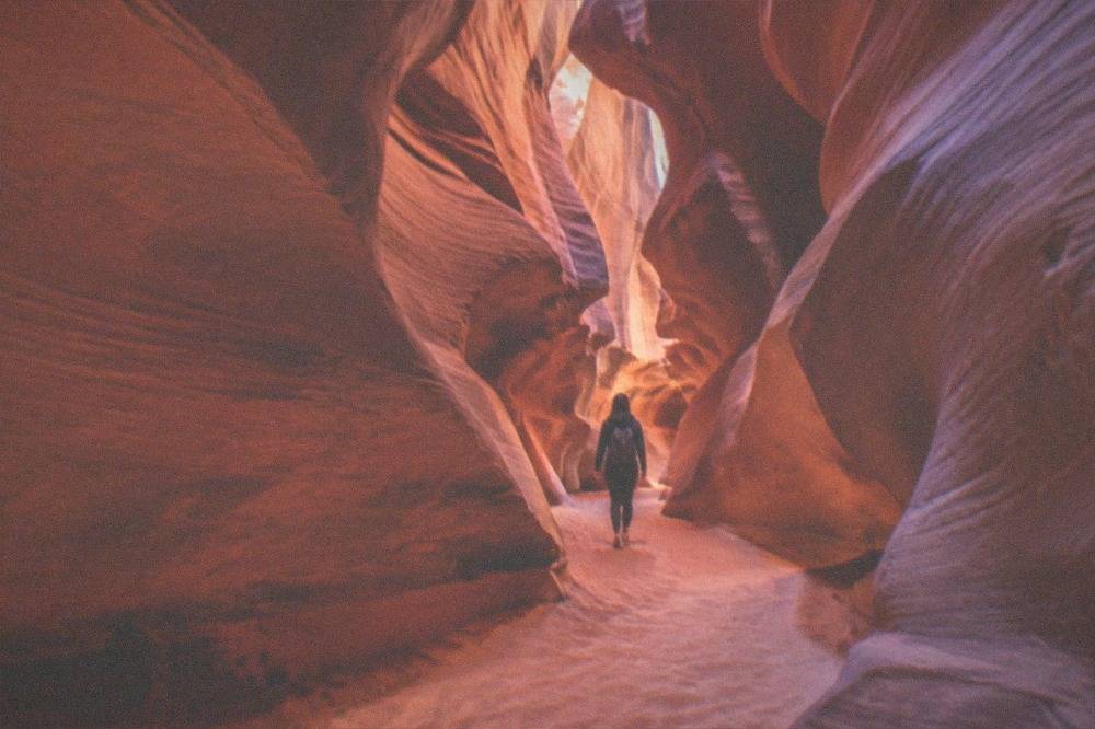 A narrow sandstone slot canyon with smooth curved walls glowing in filtered light