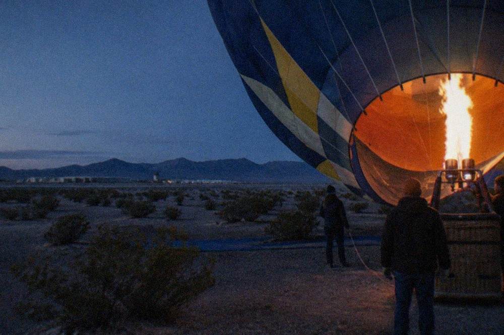 A balloon envelope being inflated on a dark desert launch field before sunrise