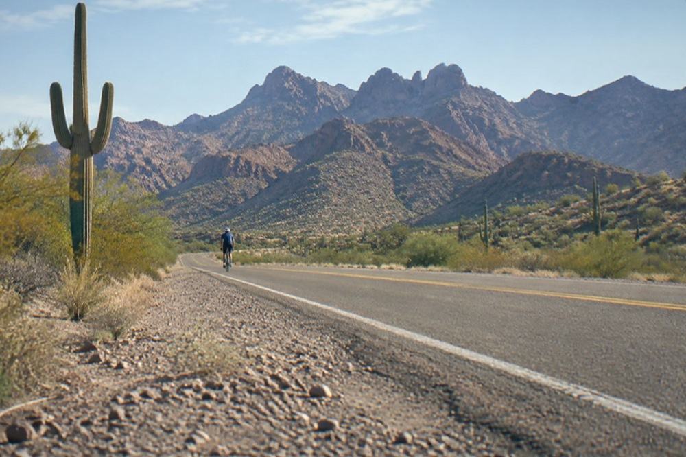A highway heading north through open desert toward distant red rock cliffs