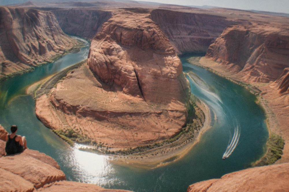 Wide view of a desert reservoir with red rock walls rising from the water