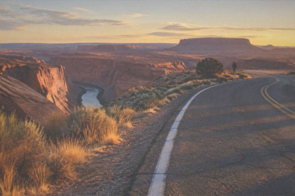 A desert highway curving toward distant mesas in late afternoon light