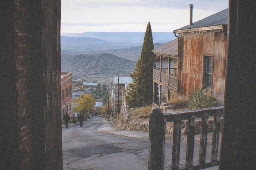 Historic brick and wood buildings on a steep narrow street overlooking a wide desert valley