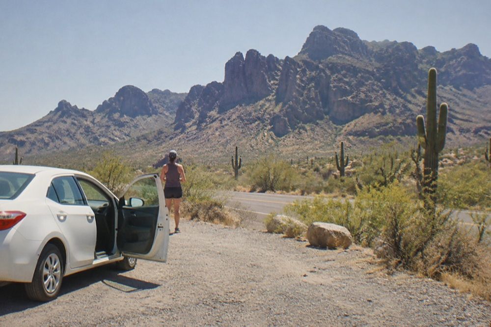 An open desert highway stretching toward distant red rock cliffs under a wide sky