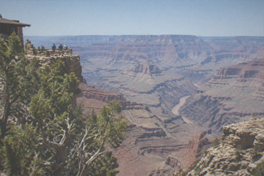 A wide canyon vista with layered rock walls descending to a river far below