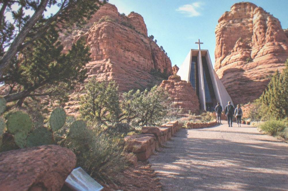 A small chapel built into a gap between red rock buttes under a clear sky