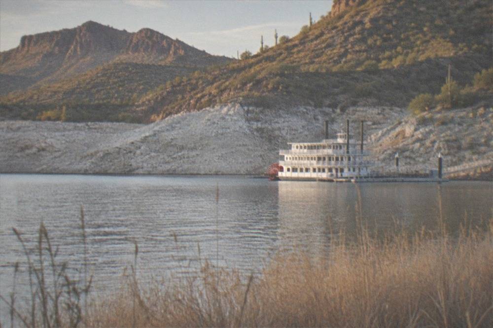Paddle steamer boat on Canyon Lake below rocky desert slopes