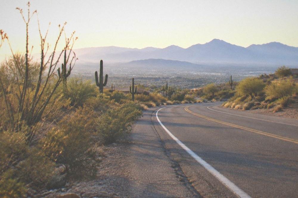 A paved road curving through open desert toward distant mountain ranges