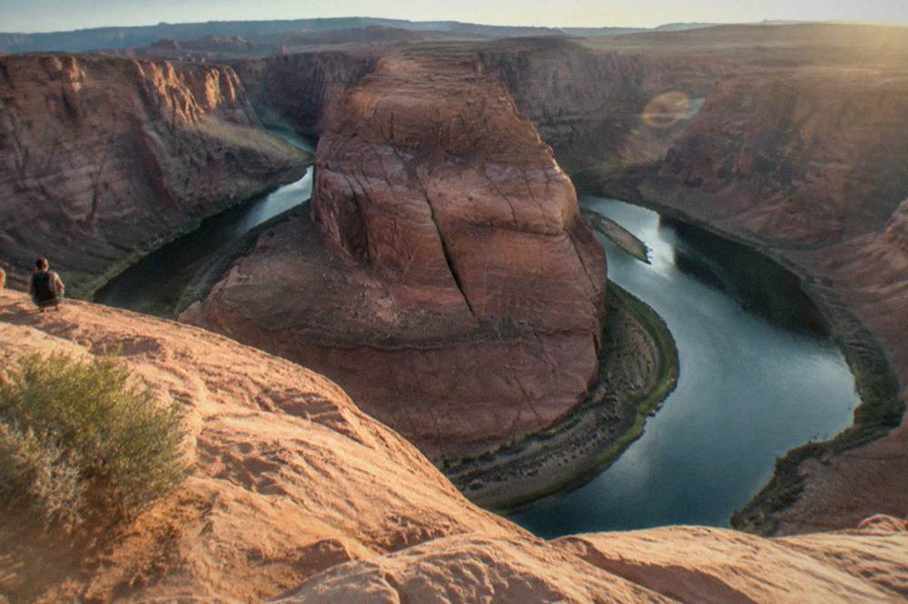 A wide river bend curving around a tall sandstone cliff under an open desert sky