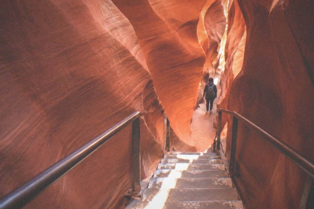 A metal staircase descending between narrow sandstone walls inside a slot canyon