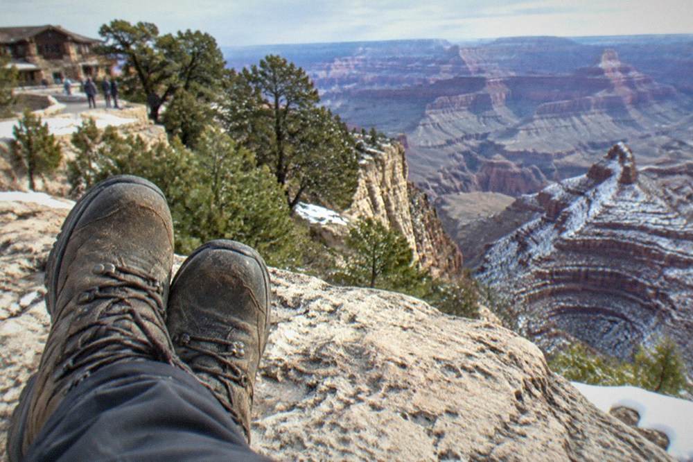 Sturdy walking shoes resting on a stone ledge above canyon layers