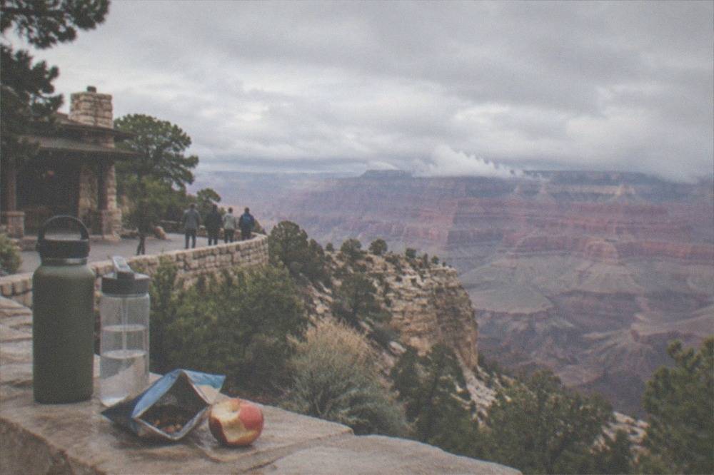 Water bottles and snack bag on a rock wall overlooking the canyon