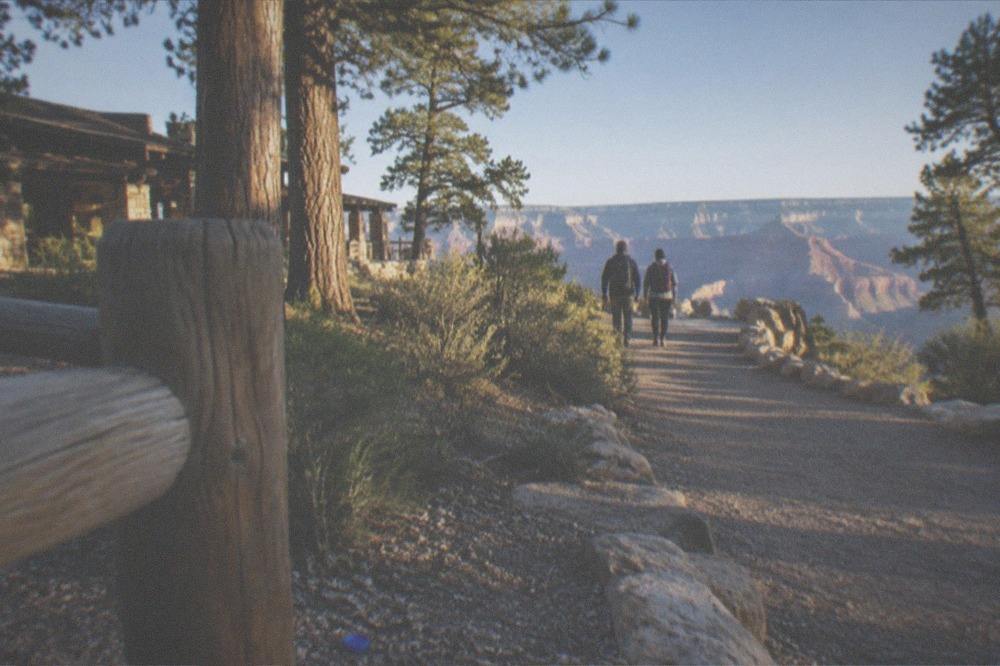 Clear trailhead sign at the rim with hikers passing in the background